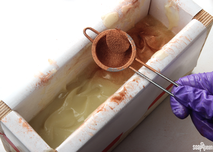 A small powder duster helps apply a thin and even layer of mica to the soap.