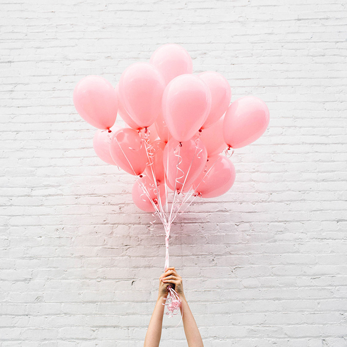 Two hands holding a bouquet of balloons